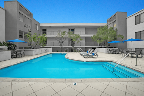 A swimming pool in front of a building with a blue sky.