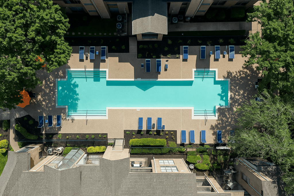 An aerial view of a pool surrounded by trees and a building.
