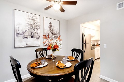 A dining room with a table set for two and a framed picture on the wall.