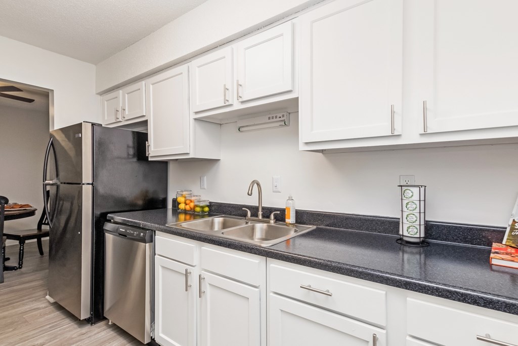 A kitchen with white cabinets and black countertops.