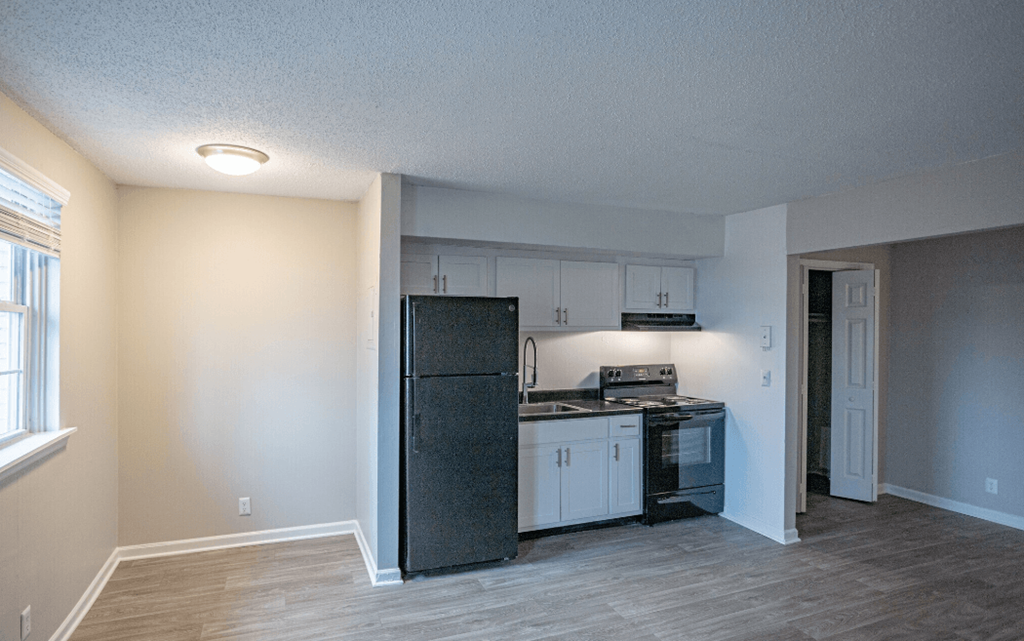 a kitchen with white cabinets and a black refrigerator