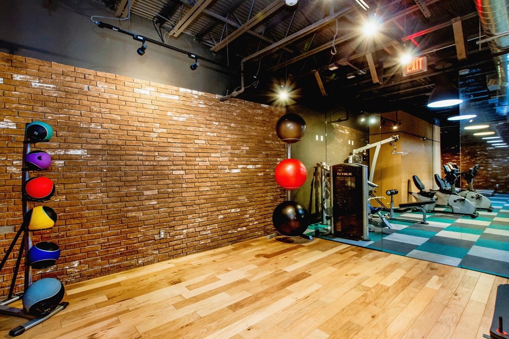 a gym with a wooden floor and a brick wall with exercise equipment