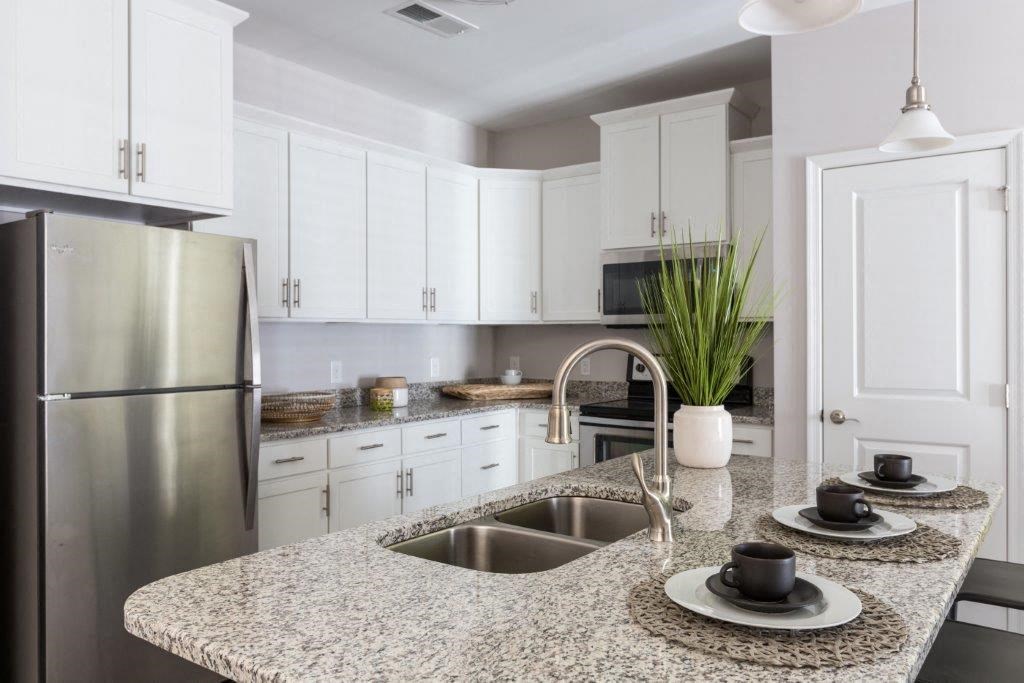a kitchen with granite counter tops and a stainless steel refrigerator