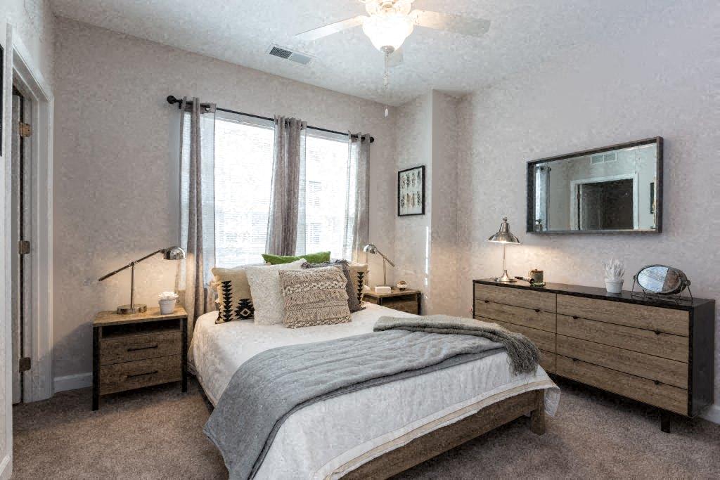 a bedroom with a bed and two dressers and a window