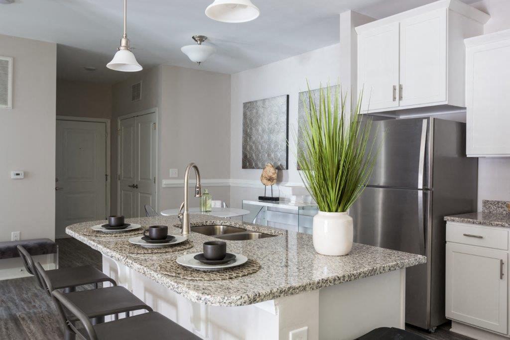 a kitchen with a marble counter top and a stainless steel refrigerator