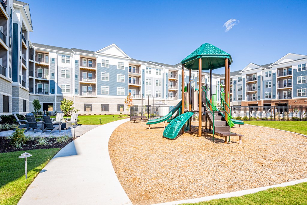 a playground with a swing set in front of an apartment building