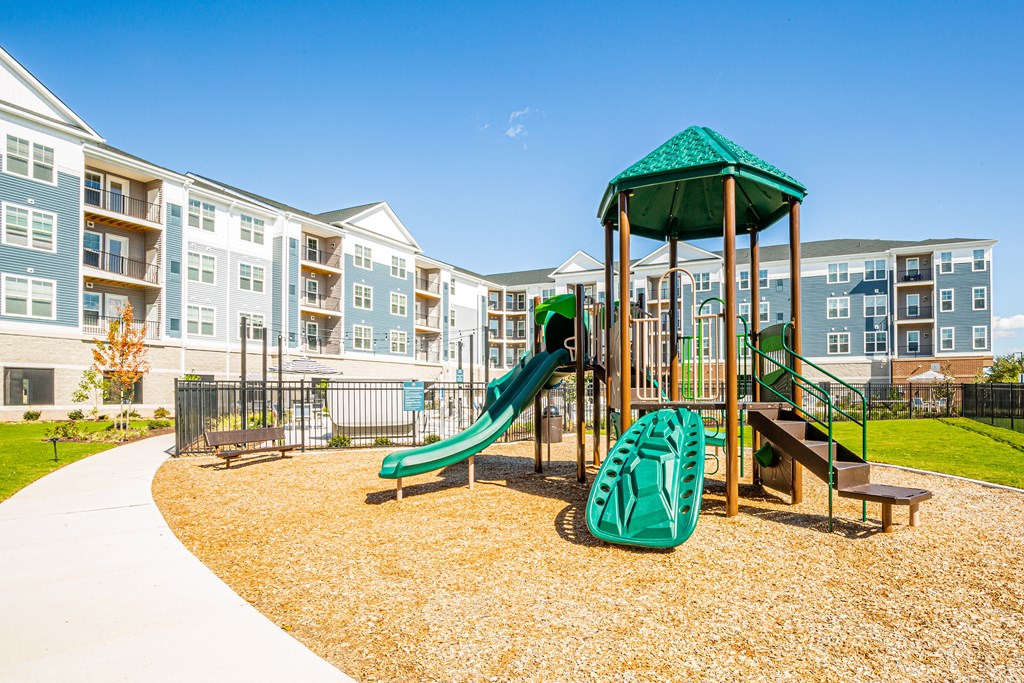 a playground with a swing set and slides in front of an apartment building