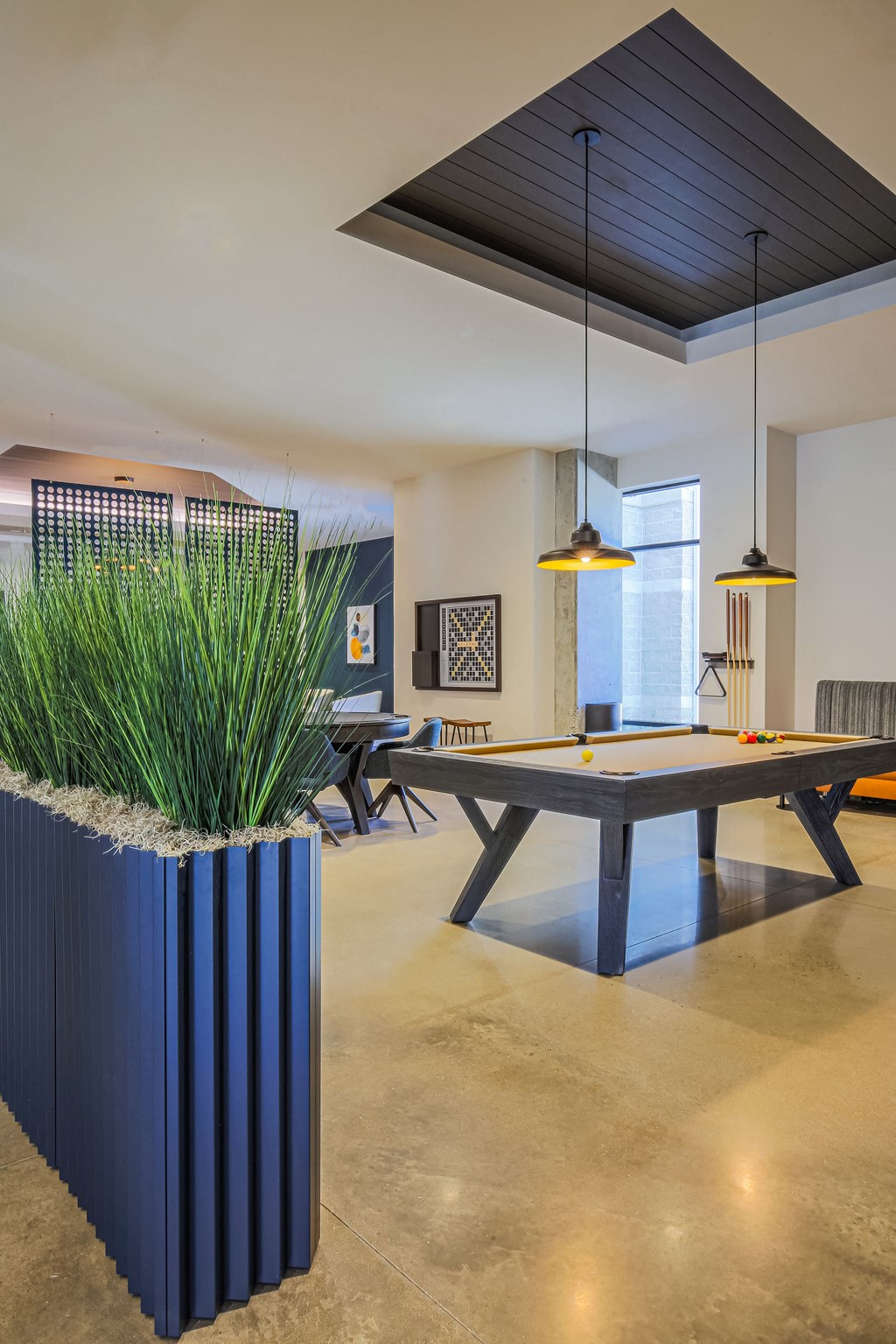 a game room with a ping pong table and a large potted plant