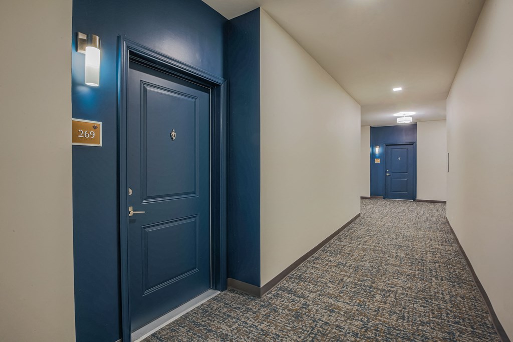 a hallway with blue doors and white walls and a carpeted floor