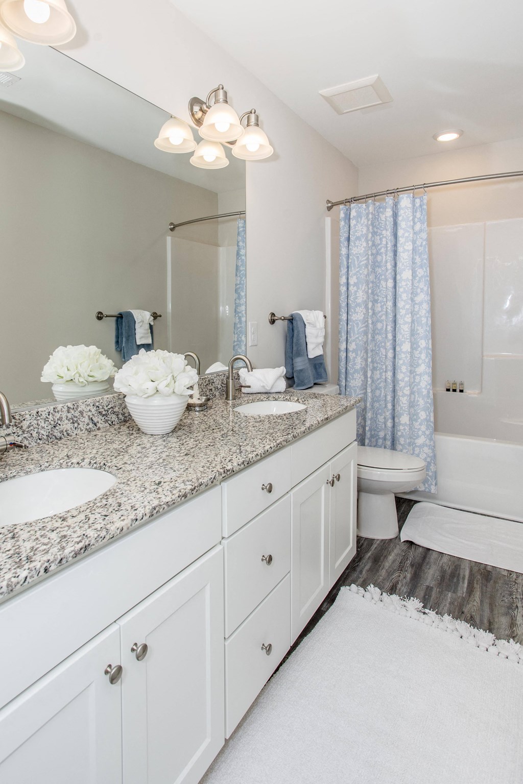 a white bathroom with granite counter tops and a toilet and sink