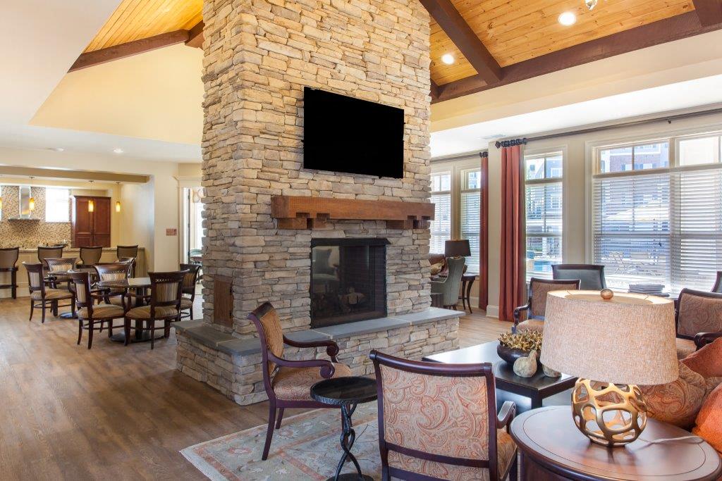 a living room with a stone fireplace and a dining room