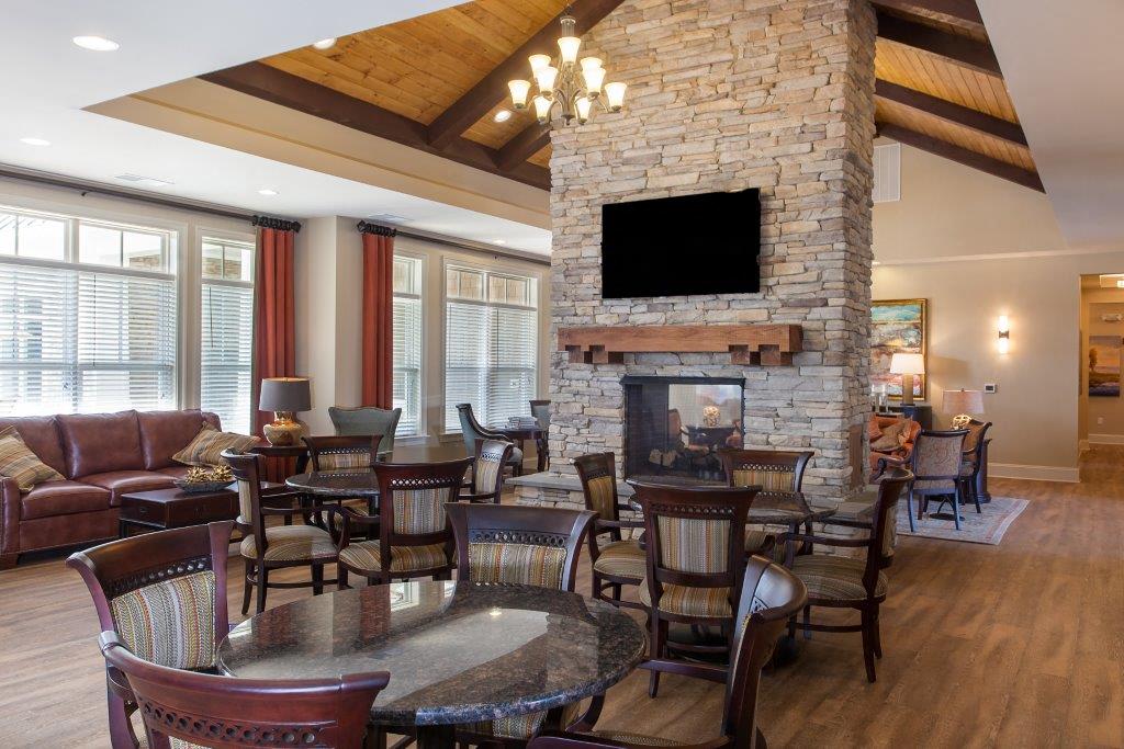 a living room with a stone fireplace and a table and chairs