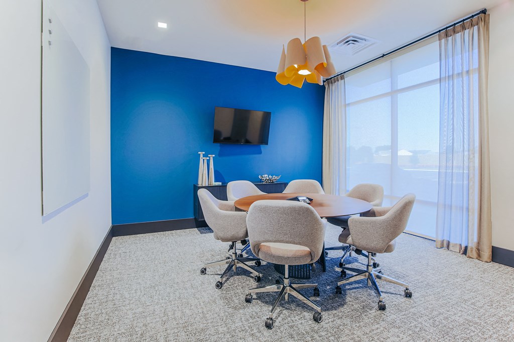 a conference room with a table and chairs and a tv