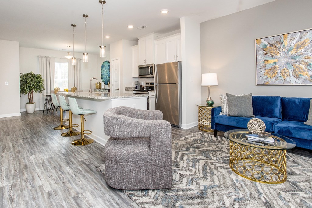 a living room with a kitchen and a couch and chairs