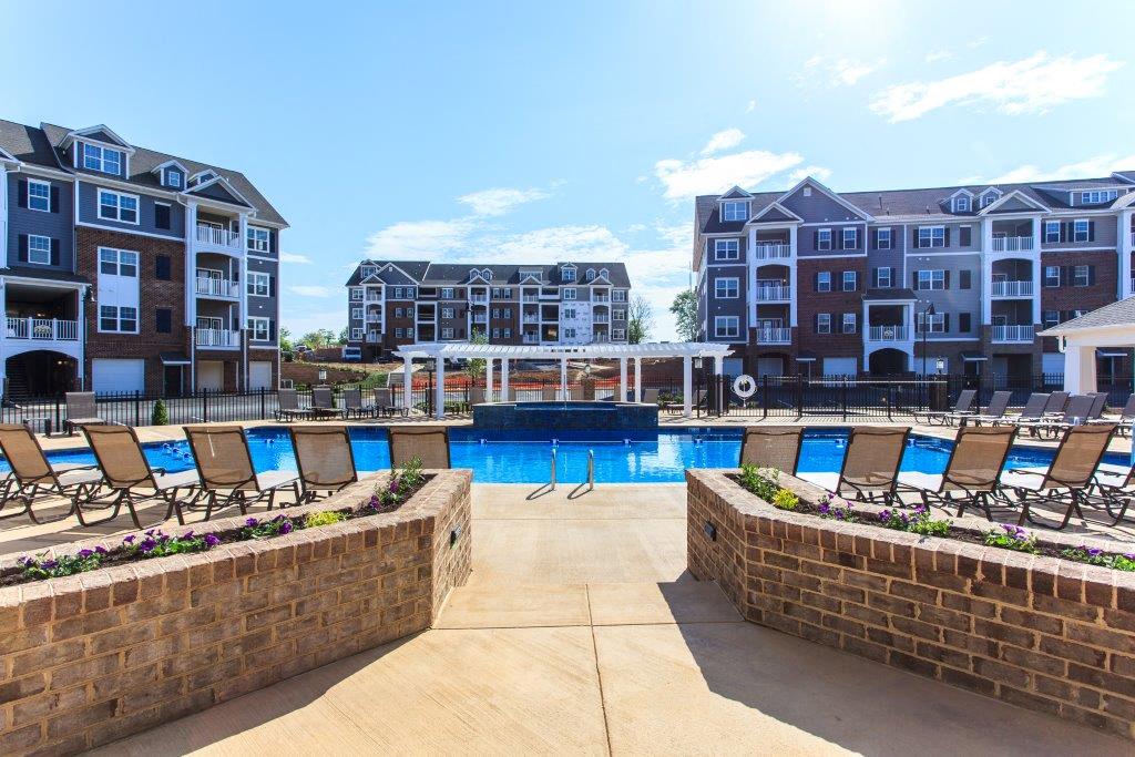 an outdoor pool with lounge chairs at the preserve at ballantyne commons apartments