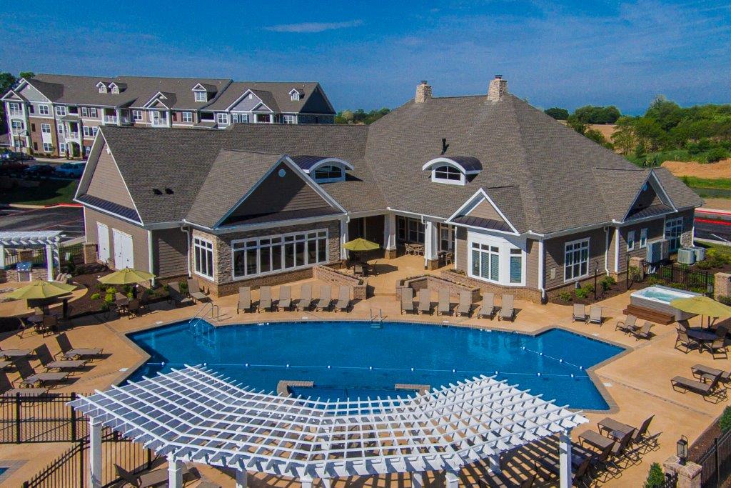 an aerial view of a large swimming pool with a mansion in the background