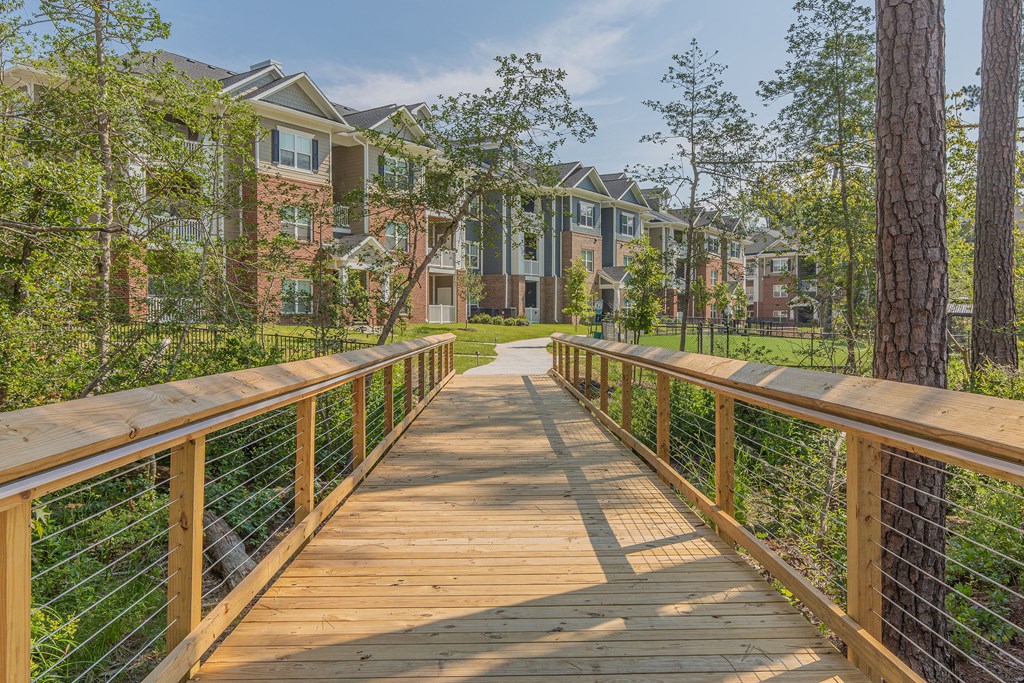 a wooden bridge with trees and houses in the background
