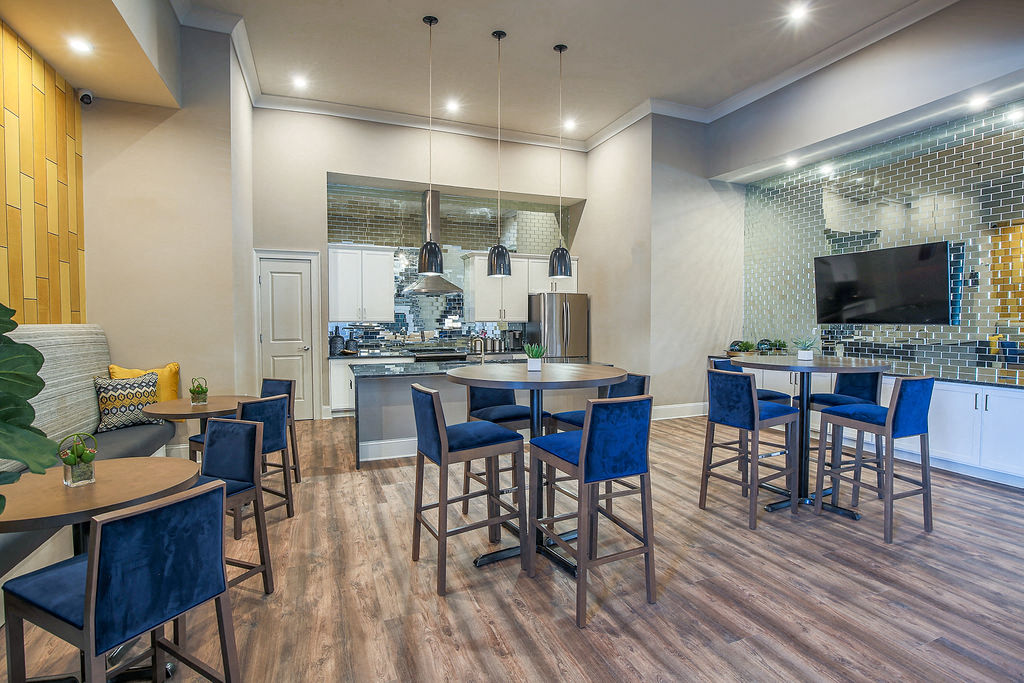a clubhouse with a kitchen and tables with blue chairs