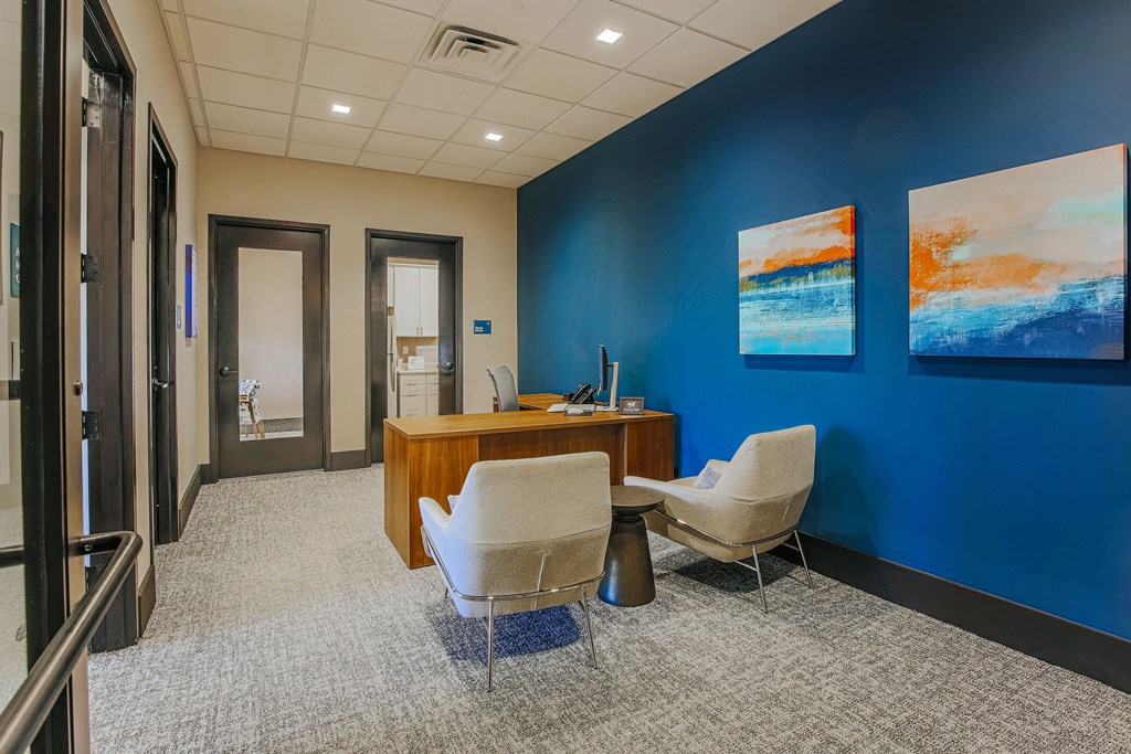 an office with two chairs and a desk and a blue wall