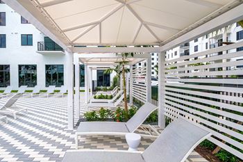 a patio with two lounge chairs and a white building at Altis Grand Kendall, Miami