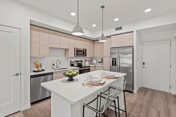 A modern kitchen with a white island and stainless steel appliances.