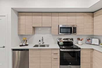 a kitchen with a stove and a sink and a microwave at Altis Grand Kendall, Florida, 33186