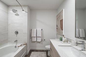 a bathroom with a tub and a sink and a mirror at Altis Grand Kendall, Miami, 33186