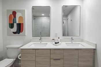 a bathroom with two sinks and a mirror at Altis Grand Kendall, Miami, FL