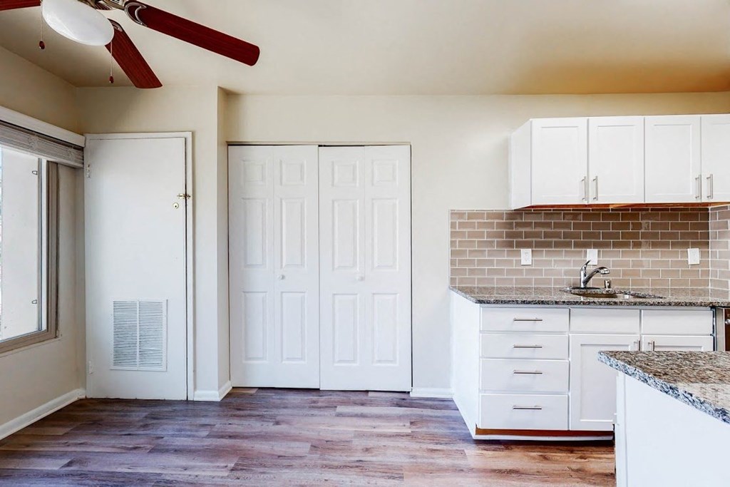 an empty kitchen with white cabinets and a sink