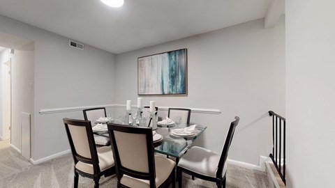 A dining room with a glass table and chairs.