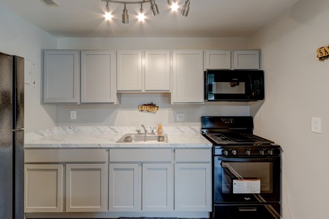 A kitchen with white cabinets and a black stove.