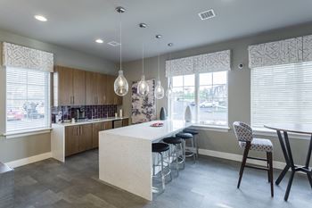 a kitchen with a large island and stools in front of a table with chairs