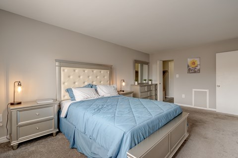 A bedroom with a blue bedspread and a white headboard.