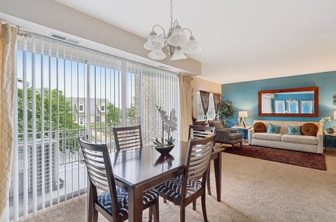 A dining room with a table and chairs and a view of the outside.