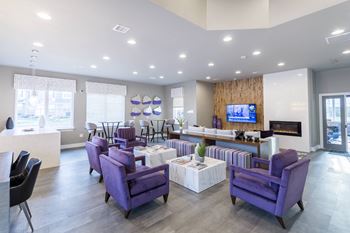 a living room with purple chairs and tables and a television