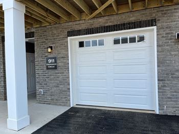 a white garage door in front of a brick building