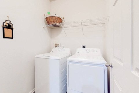 a white laundry room with two washes and a dryer