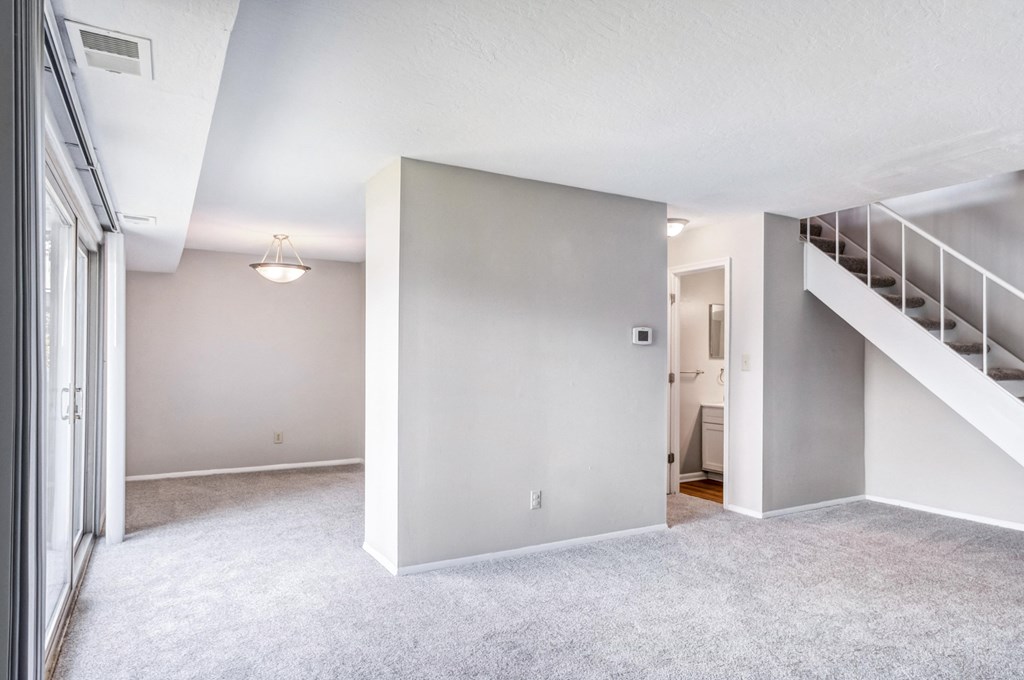 an empty living room with a staircase in a home with white walls