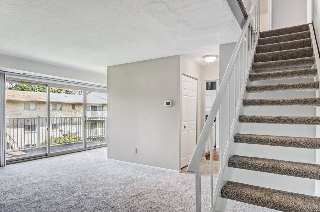 a living room with carpeted stairs and a door to a balcony