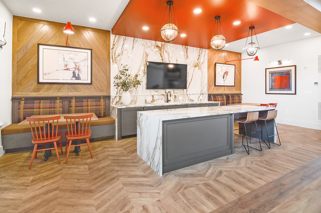 a room with a table and chairs and a kitchen with a sink and a television