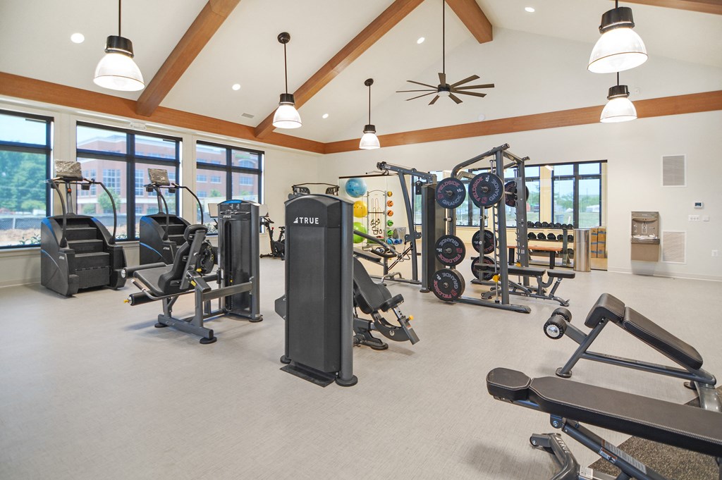 a spacious fitness center with cardio equipment and windows