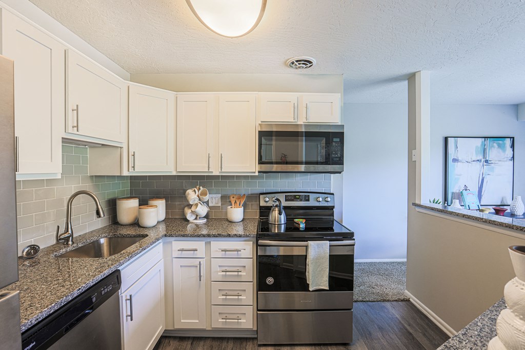 a kitchen with white cabinets and black appliances