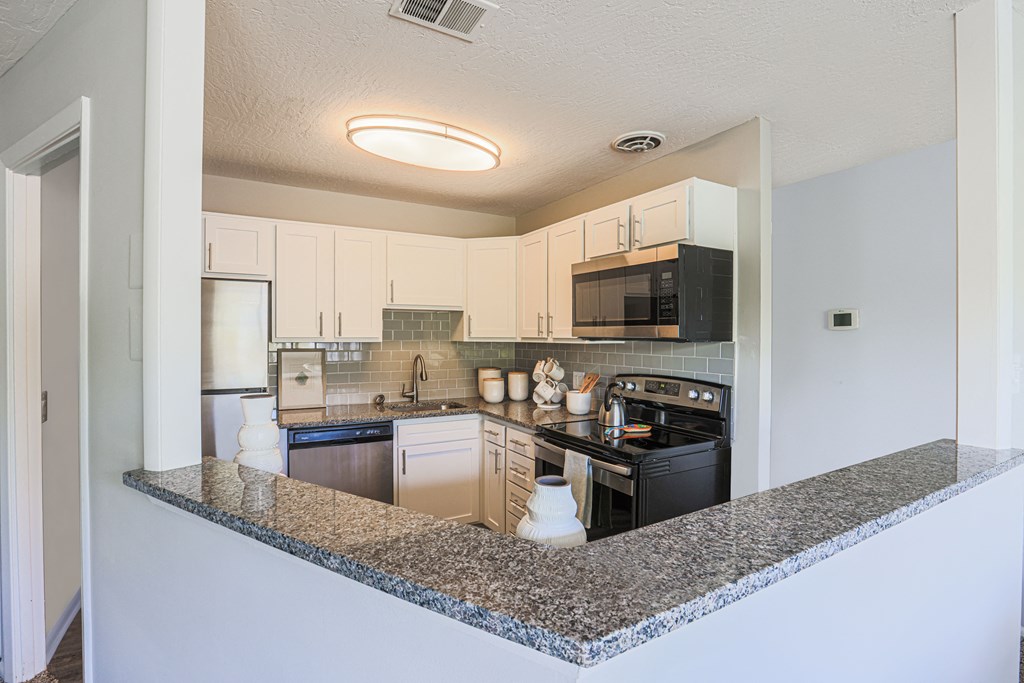 a kitchen with white cabinets and granite countertops