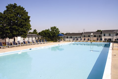 A large outdoor swimming pool with blue water and lounge chairs.