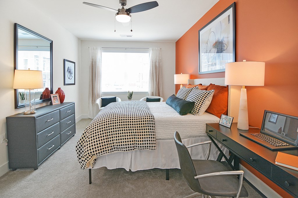 a bedroom with an orange accent wall and a bed with a checkered comforter