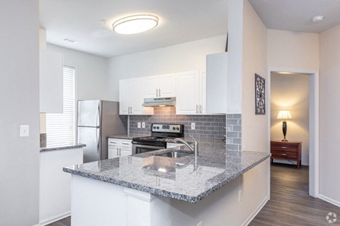 a kitchen with white cabinets and a granite counter top