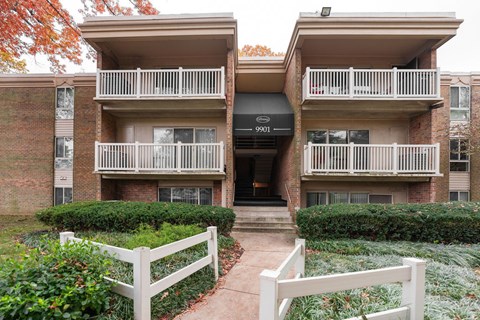 Apartment building with a white fence in front.