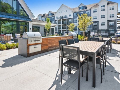 a patio with a barbecue grill and a table and chairs