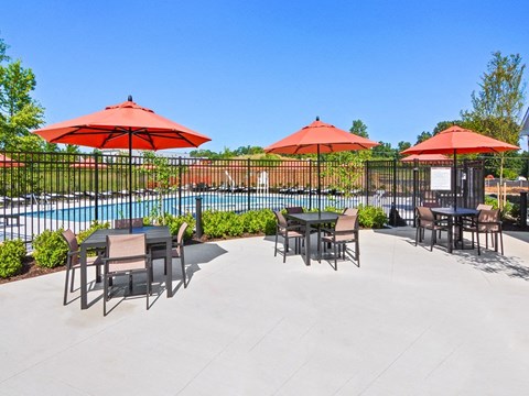a patio with tables and umbrellas next to a pool