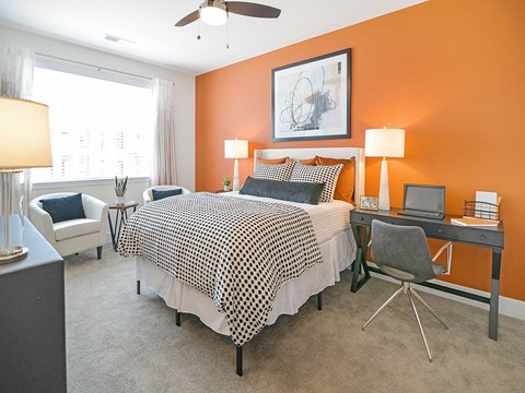 a bedroom with an orange accent wall and a black and white bed